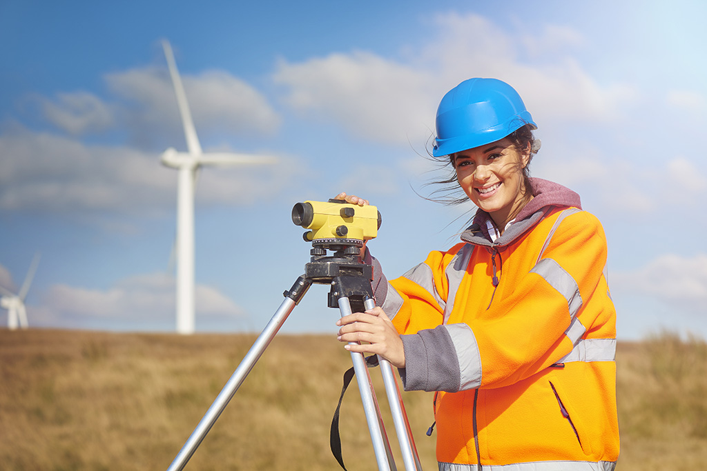 femme géomètre qui sourit et qui utilise son appareil à mesurer dans un chantier d