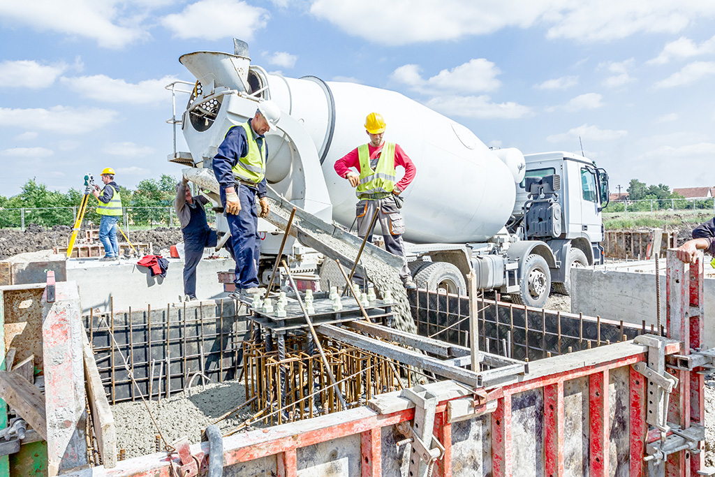 engin de chantier bétonnière et deux ouvriers qui gèrent l