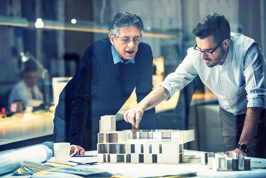 deux hommes dans un bureau entrain de travailler sur un maquette d