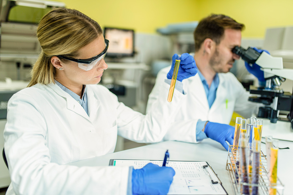 dans un laboratoire deux techniciens qualité un homme et une femme en blouse blanche et portant des lunettes de protection l