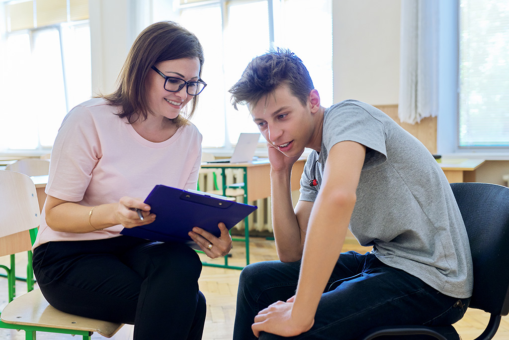 dans une salle de classe éducatrice jeunes enfants qui discute avec un adolescent