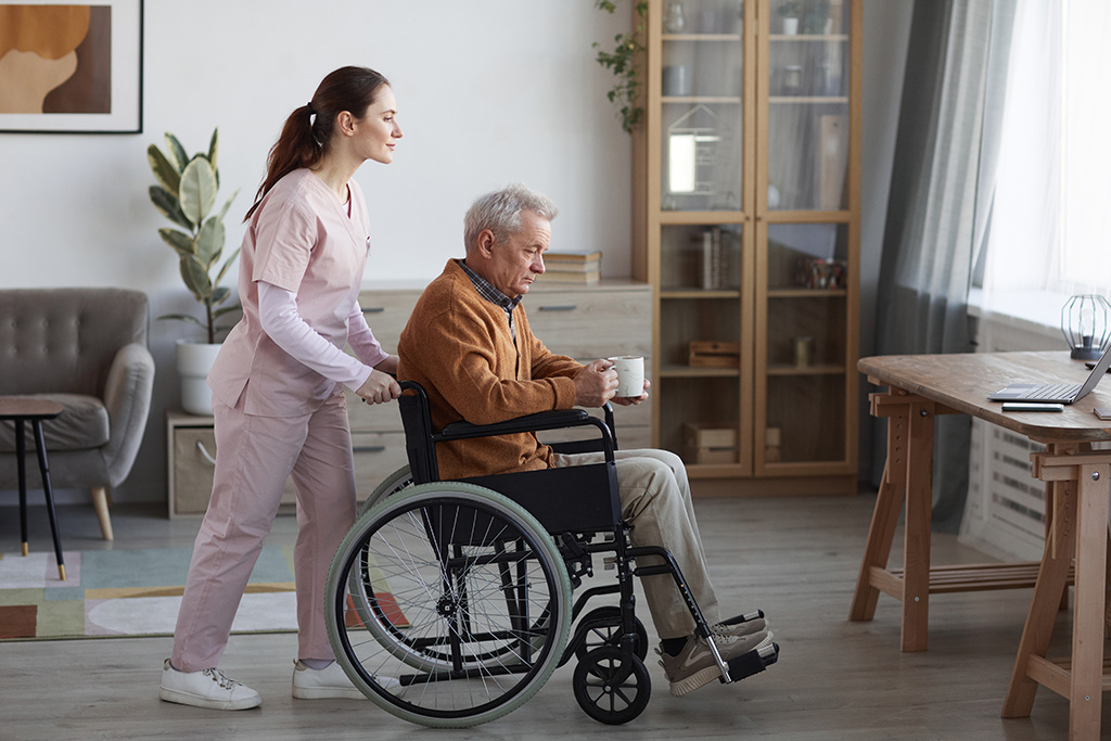 femme accompagnante qui pousse un homme âgé en fauteuil roulant 