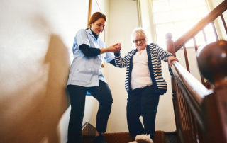 soignant qui aide une femme âgée à descendre les escaliers