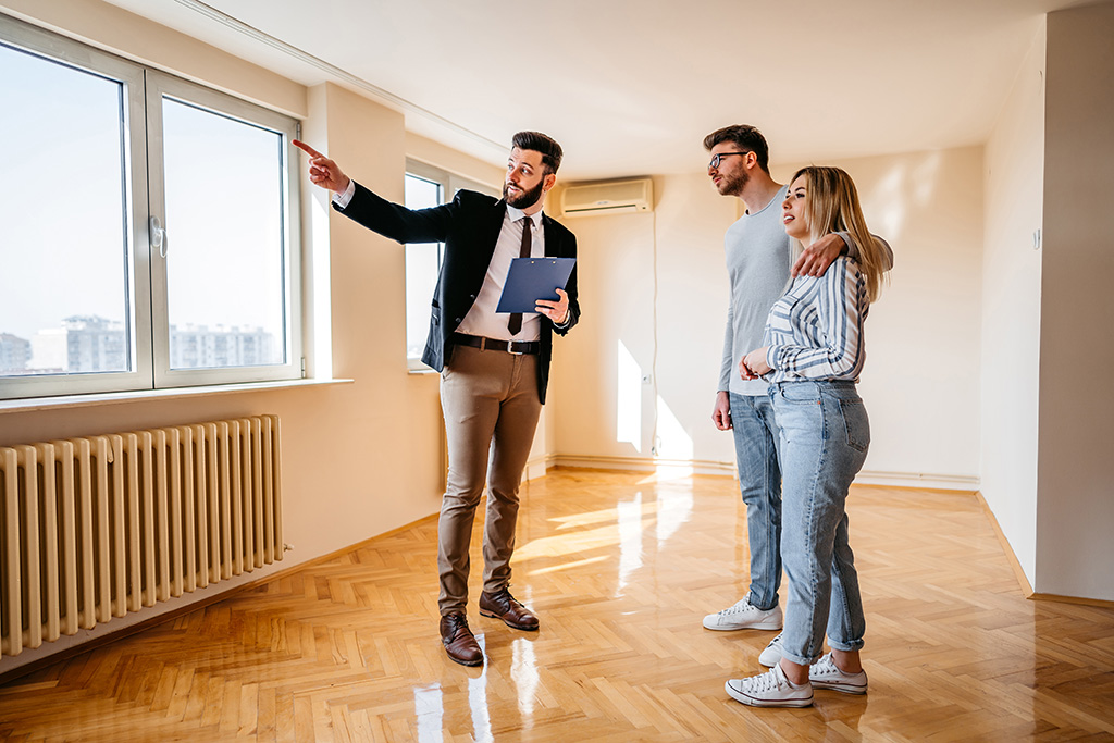 agent immobilier faisant visiter un appartement à un couple