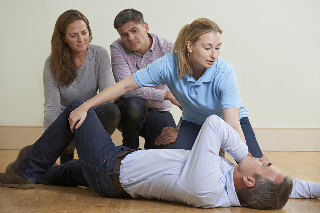 groupe de 4 personnes en formation gestes de premiers secours dont un homme allongé a qui on prodigue un mouvement de PLS