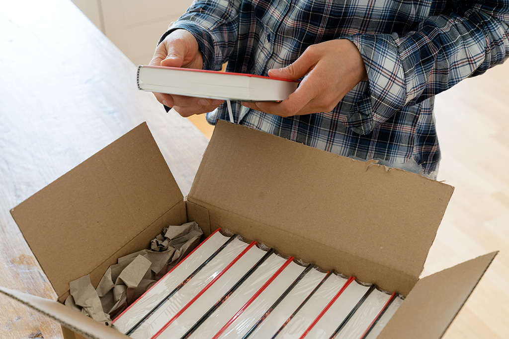 Auteur ouvre un carton avec des échantillons de son nouveau livre et vérifie la couverture rigide 