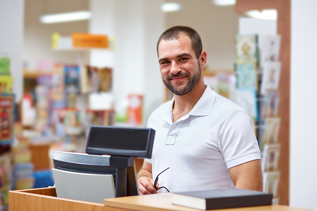 portrait vendeur homme en librairie se tenant derrière sa caisse