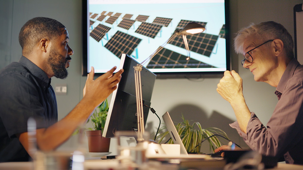 deux techniciens en réunion discutant de panneaux solaires avec la projection murale de la présentation